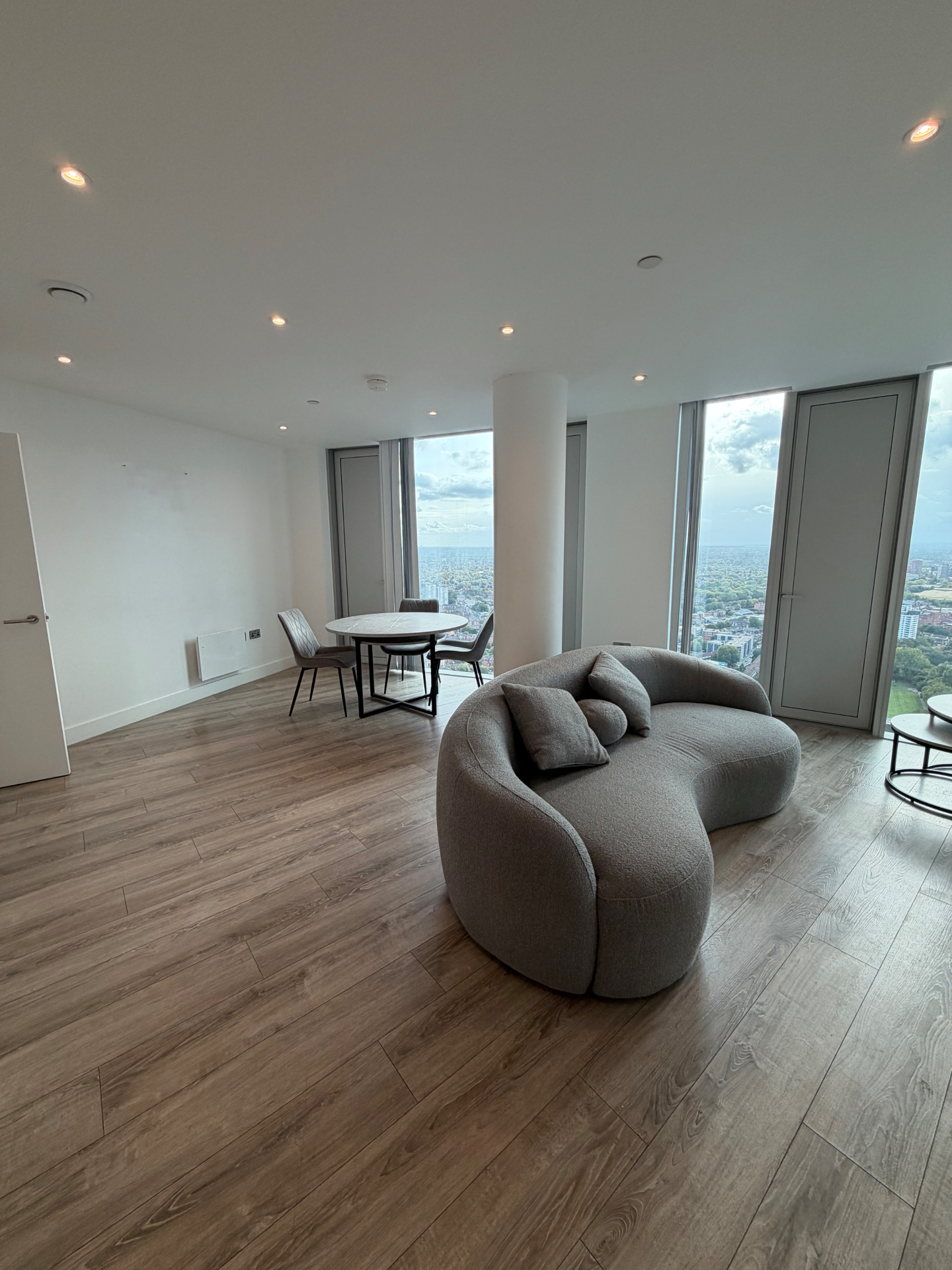 Three60 apartment living room with curved sofa and panoramic city views
