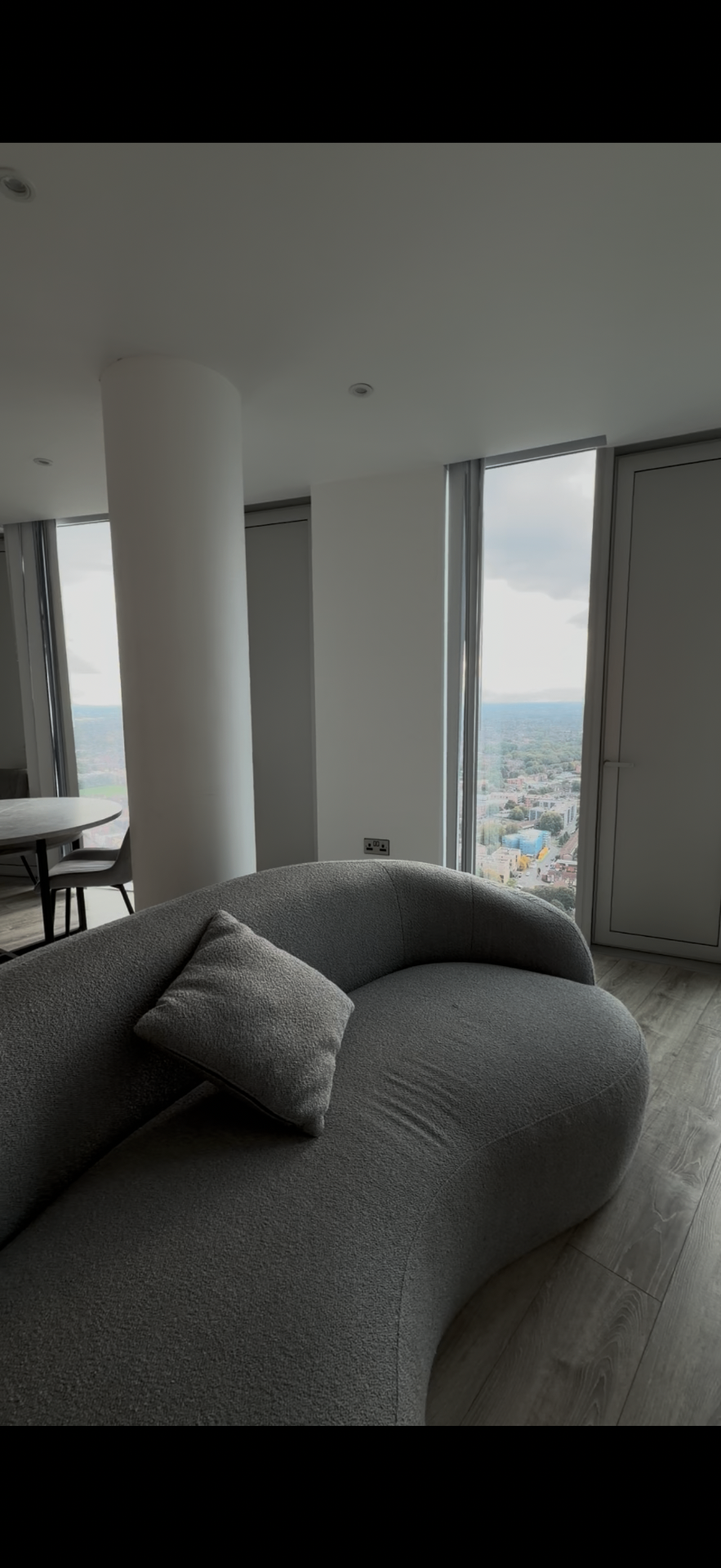 Three60 — living room with curved sofa and floor-to-ceiling city views